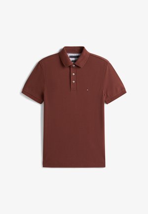 Burgundy-paitainen poolopaita, joka on valmistettu teksturoidusta puuvillasta. Siinä on kolme nappia edessä ja pieni logo vasemmassa rinnassa. Lyhyet hihat.