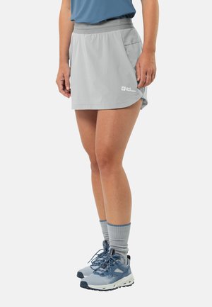 Grijze sportieve skort van lichtgewicht materiaal, met een elastische tailleband en een zijzak, gecombineerd met blauwe wandelschoenen en grijze sokken.