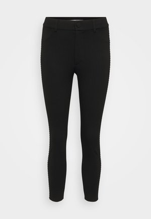 Leggings negros de tela elástica, con un diseño ajustado, cierre de botón y costuras decorativas en los laterales.