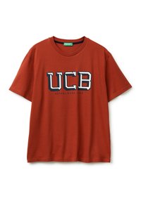 Camiseta de algodón naranja con mangas cortas, cuello redondo, que presenta un logo impreso de "UCB" y el detalle "ESTABLECIDO 1965" en azul marino.