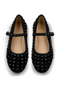 Finos zapatos Mary Jane de ante negro con puntera redonda, que cuentan con una correa y numerosos clavos negros en la parte superior. Forro interior suave.