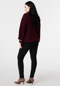 Bordeaux gebreide trui met opgeblazen mouwen, gecombineerd met zwarte broek met aan de zijkanten paillettenaccenten. Dierprint hoge hakken laarzen.