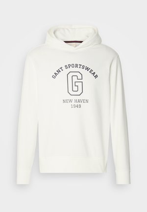Bílá mikina s kapucí se znakem "GANT SPORTSWEAR" a velkým logem "G" v námořnické barvě, s žebrovanými manžetami a spodním lemem. Hladká textilie.