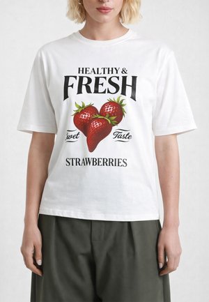 Persona che indossa una maglietta bianca con tre grandi fragole rosse e il testo "Gusto Dolce Sano e Fresco Fragole" sulla parte anteriore.