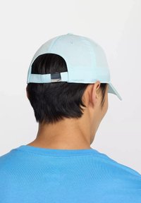Gorra azul claro con visera curva y cinta ajustable en la parte posterior. Presenta un acento plateado en la cinta. Textura lisa.