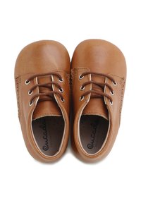 Zapatos de cuero marrón con punteras redondeadas, cuentan con ojales de metal y cordones marrones. El interior tiene una textura perforada para ventilación.