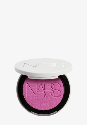 Boîtier rond et compact avec un couvercle blanc affichant le logo NARS, contenant un fard à paupières rose vif scintillant avec l'inscription NARS en relief.