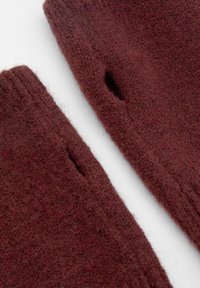 Burgundy neulekangas, jossa on pehmeä rakenne. Yhdellä sivulla on aukko-yksityiskohta ja ylhäällä ribbireuna. Kaksi päällekkäistä kappaletta esitetty.