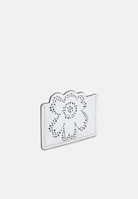Tarjetero de cuero blanco con diseño floral troquelado, borde superior redondeado y costuras visibles. Superficie texturizada con pequeñas perforaciones.