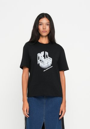 T-shirt graphique en coton noir avec un design de logo blanc superposé sur le devant. Manches courtes et coupe décontractée, associé à une jupe en denim.