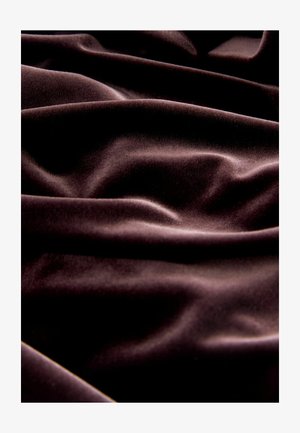 Tissu en velours brun foncé avec une texture lisse, présentant des drapés doux et de légers plis partout. La lumière scintille à sa surface.