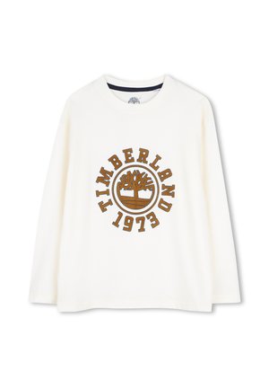Chemise blanche à manches longues avec col rond, logo Timberland marron et texte "1973" sur le devant.