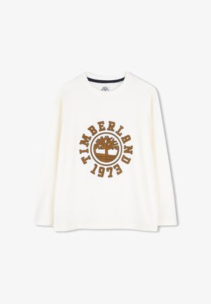 Biała koszula z długim rękawem z okrągłym dekoltem, brązowym logo Timberland i tekstem "1973" z przodu.