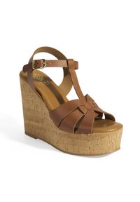 Sandale escarpin en cuir marron avec plateforme en liège, présentant un design en T et une bride de cheville ajustable. Texture lisse avec des détails de sangles croisées.