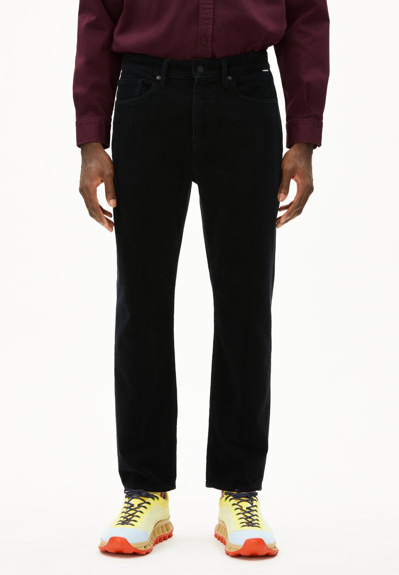 Zwarte corduroy broek met een recht gesneden ontwerp, met een klassieke vijf-pocket stijl. Draagt met gele en grijze sportschoenen.