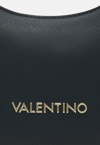 Svart texturerad läderväska med en framträdande guld "VALENTINO"-logotyp. Slät yta med rundade kanter och detaljerad sömnad.