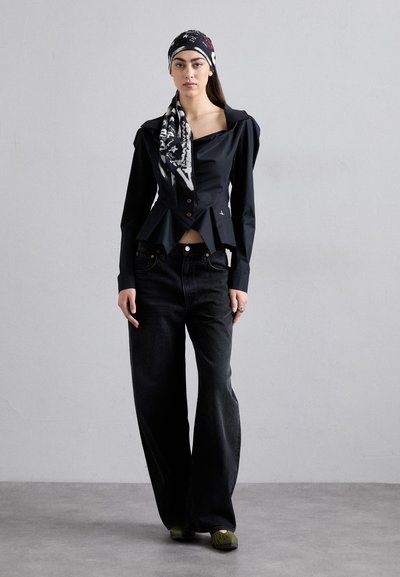 Top peplum negru cu un guler mare și închidere cu nasturi, asociat cu blugi largi de culoare închisă. Accesoriile includ o eșarfă cu model și pantofi verzi.