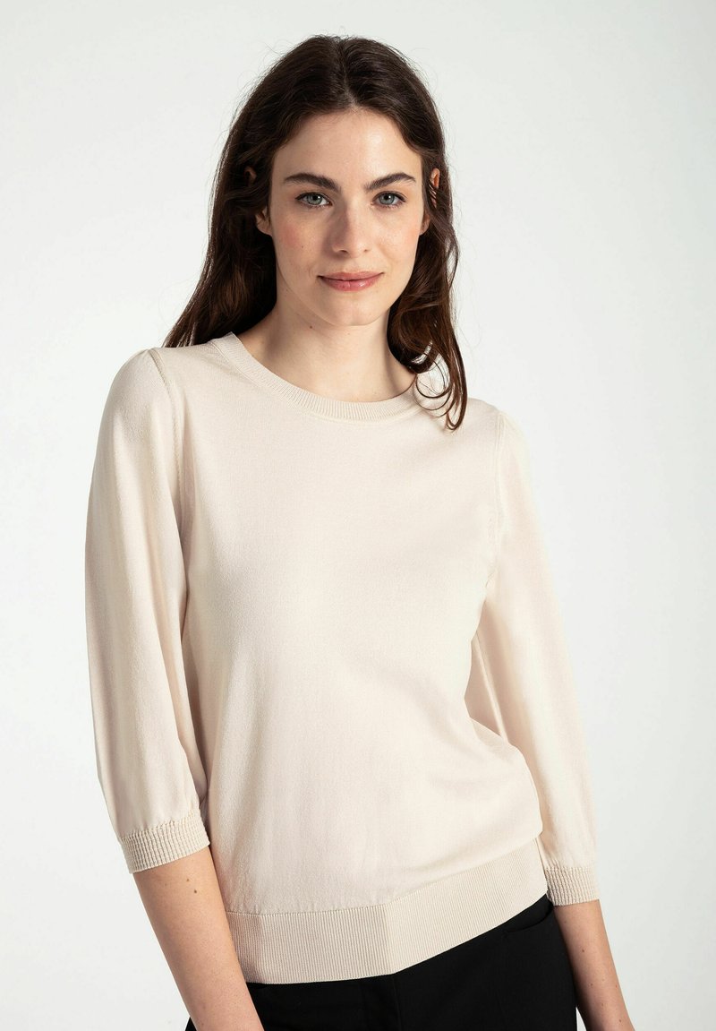 Helles beiges Strickpullover mit Dreiviertelärmeln, rundem Halsausschnitt und gerippten Akzenten an den Ärmelabschlüssen und dem Saum. Glatte Textur, schlichtes Design.