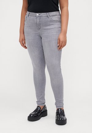 Sivé skinny džínsy z denimu s prednými vreckami a priliehavým strihom, skombinované s čiernymi platformovými topánkami so študovanými akcentmi.