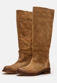 Bottes en daim beige jusqu'au genou avec des orteils ronds lisses, des détails cousus et un petit talon en bois empilé. Texture douce et matériel minimal.