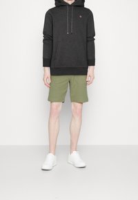 Donkergrijze capuchonsweatshirt met trekkoordjes, voorzak, olijfgroene korte broek en witte sneakers. Eenvoudig ontwerp, minimale accenten.