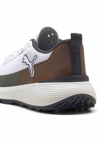 Vit och brun golfsko med texturerad överdel, grå accenter och distinkt Puma-logotyp. Har en gummisula med mönster för bra grepp.