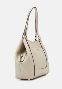 Beige leren emmer handtas met dubbele schouderbanden, gouden hardware, voork pocket en ritssluiting op een eenvoudige witte achtergrond.