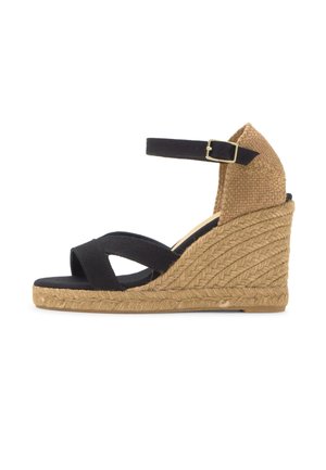 Crna tkanina klompa sandala s remenom oko gležnja i potplatom te petom od tkanog jutnog materijala, bočni prikaz na bijeloj pozadini.