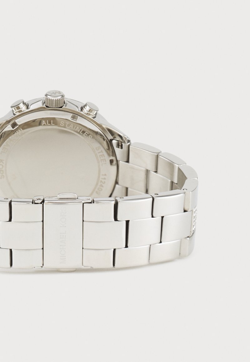 Montre en acier inoxydable argenté avec un bracelet en maillons poli et un boîtier rond. Comprend trois boutons-poussoirs et une surface lisse et réfléchissante.