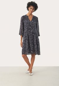 Marineblauwe bloemen midi-jurk met driekwartmouwen, V-hals en uitlopende rok, gemaakt van lichtgewicht stof. Draagt met zilveren flats.