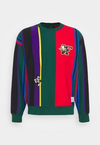 Pull à manches longues avec des rayures verticales vertes, rouges, noires, violettes, jaunes et bleues arborant des illustrations de Félix le Chat sur le devant.