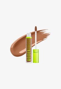 Tube de correcteur NYX Wonder Stick avec un capuchon vert néon ouvert et un applicateur, montré avec une trace de fond de teint beige derrière.