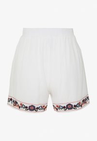 Shorts blancs avec une ceinture élastique, ornés d'une broderie florale colorée le long de l'ourlet et dotés d'une texture légère et douce.