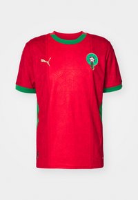 Maglietta da football rossa a maniche corte con accenti verdi, caratterizzata da un motivo testurizzato di stelle, logo Puma e un emblema circolare marocchino sul petto.