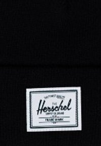 Crna pletena kapa s bijelom pravokutnom etiketom sa zelenim rubom, na kojoj je ispisano "Herschel" rukopisom i pojedinosti o proizvodu.