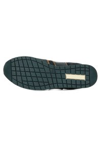 Semelle de sneaker noire avec un motif en grille texturé, présentant un accent beige clair et des rayures brunes sur le côté. Matériau en caoutchouc.