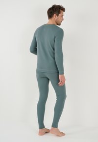 Men's thermal set in soft, teal fabric. Long-sleeve top and fitted leggings with ribbed cuffs. Simple, seamless design with a comfortable fit.