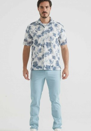 Chemise à manches courtes à fleurs en bleu et blanc, associée à un pantalon bleu clair. Matériel en coton, design à boutonnières, avec col et poches frontales.
