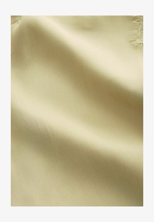 Blødt, lys gult stof med en glat tekstur og en let glans. Har delikat broderi langs den ene kant, som fremhæver håndværksdetaljerne.