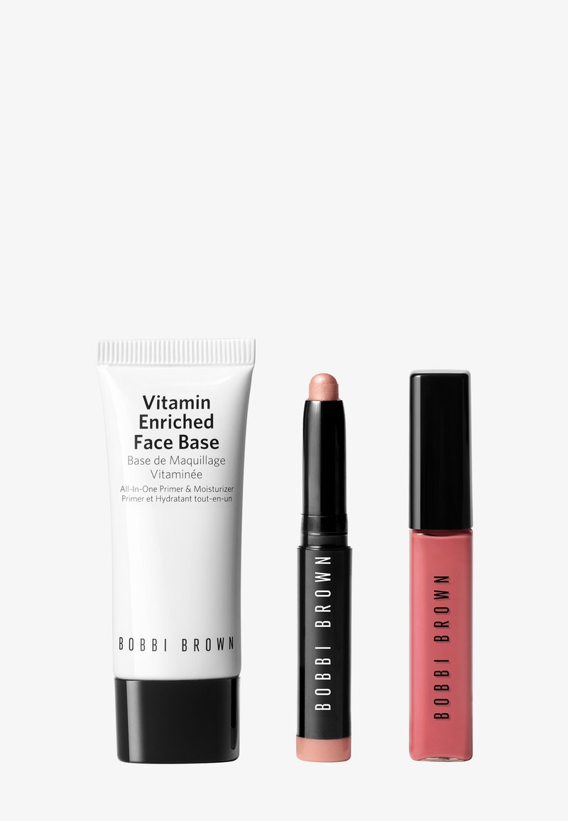 Ensemble de trois produits cosmétiques : un tube blanc avec des inscriptions noires, un bâton noir de couleur rose clair et un gloss à lèvres liquide rose, tous de Bobbi Brown.