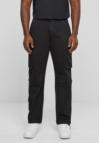 Pantalons cargo noirs avec une coupe décontractée, dotés de poches latérales et d'un tissu en coton durable. Assortis à des baskets blanches pour créer un contraste.