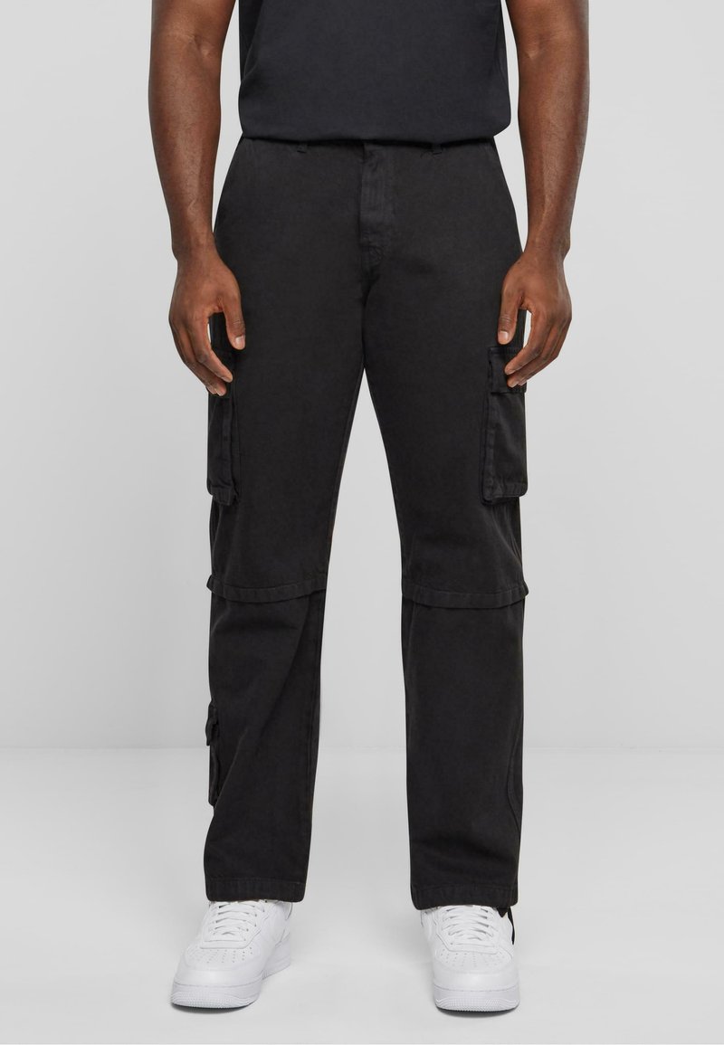 Pantalons cargo noirs avec une coupe décontractée, dotés de poches latérales et d'un tissu en coton durable. Assortis à des baskets blanches pour créer un contraste.