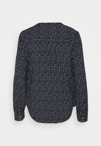 Marineblaues Langarmshirt mit weißem Punktmuster, Knopfdetails an den Bündchen und einer lockeren Passform. Es verfügt über eine Rückenpasse und eine Falte.