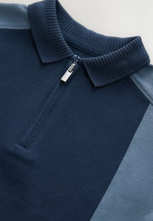 Marineblå poloshirt med kvart lynlås. Har struktureret stof og en glat skulderpanel i en lysere blå nuance.