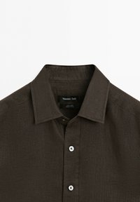 Dark brown linen shirt with classic collar and white buttons, Massimo Dutti brand label visible inside the neckline.