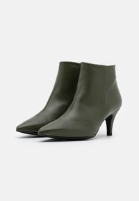 Grüne Leder-Stiefeletten mit spitzer Zehenpartie und schlankem Absatz. Glatte Textur, minimalistisches Design, mit einem Schaft, der über den Knöchel reicht.