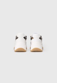 Fehér sneakers pár barna mintás részletekkel és gumi talppal, hátulról, sima világos háttér előtt bemutatva.