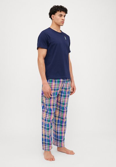 T-shirt de algodão azul-marinho com um pequeno design bordado, combinado com calças de flanela xadrez multicoloridas com padrões verdes, azuis, rosas e amarelos.
