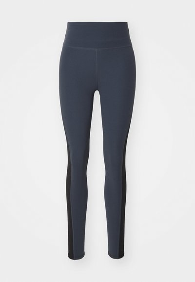 Sötétkék, elasztikus anyagból készült leggings, fekete oldalsó panelek és magas derekú szabással. Simább textúrájú, testhezálló dizájn.