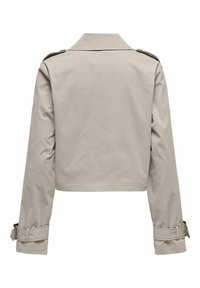 Veste courte beige avec une texture lisse, un large col et des manches longues. Dispose de poignets à boutons et d'épaulettes pour le détail.